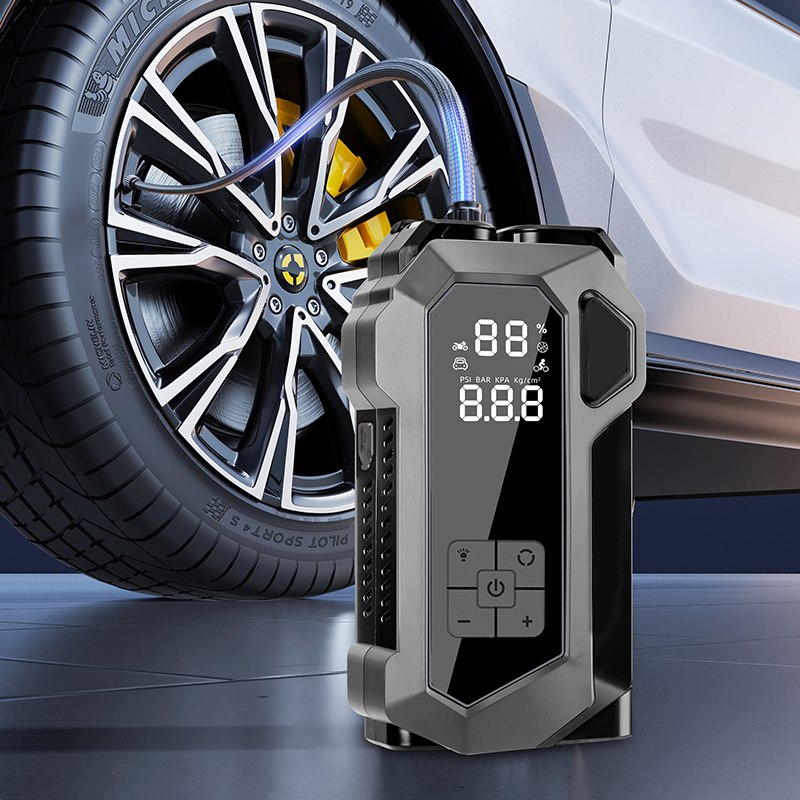 Avviatore emergenza auto 4-in-1 grigio con display LCD e torcia LED vicino alla ruota