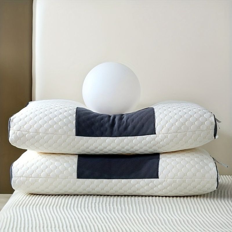 Cuscino ergonomico bianco sagomato con inserti scuri, impilato su letto