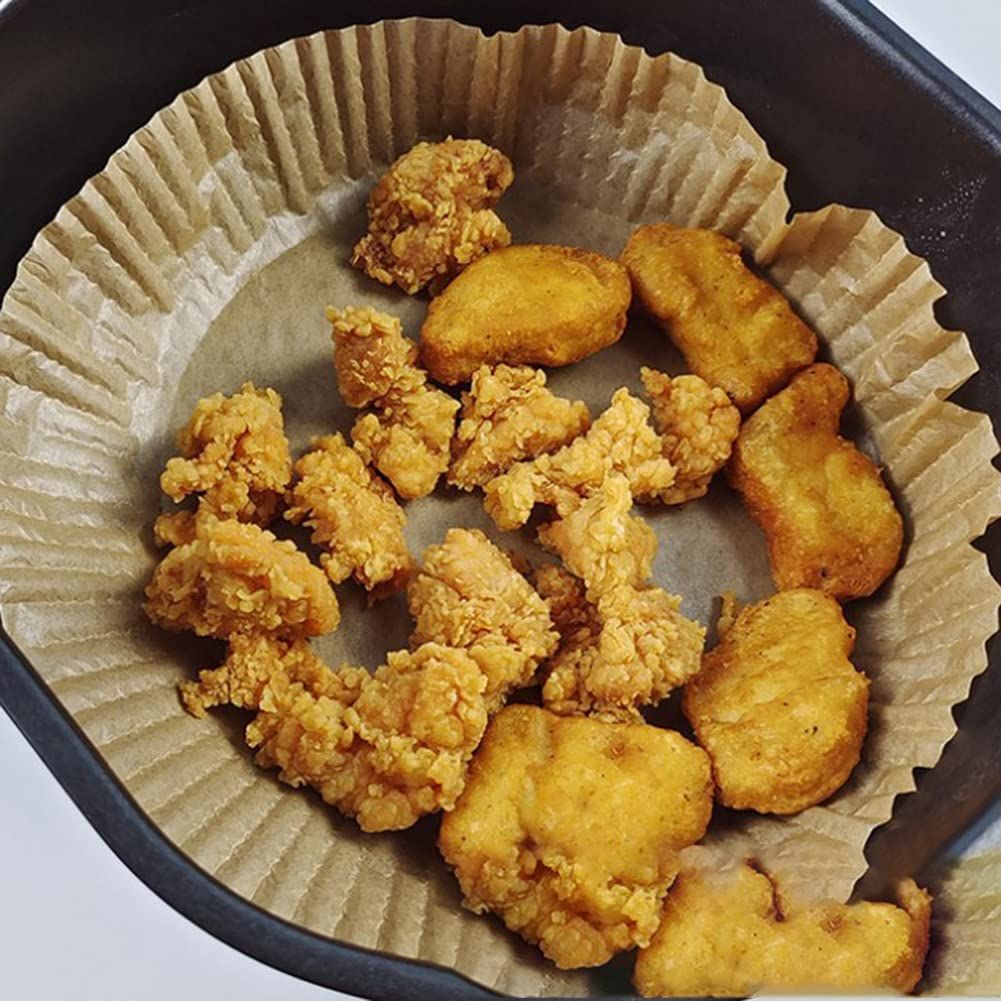 Fodera rotonda in carta per friggitrice ad aria con alimenti fritti
