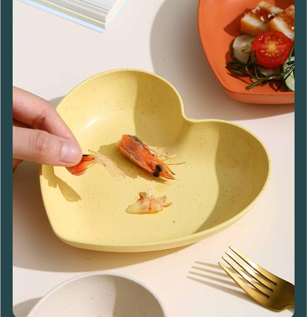 Ciotola a forma di cuore in plastica gialla con gamberi, tenuta con la mano