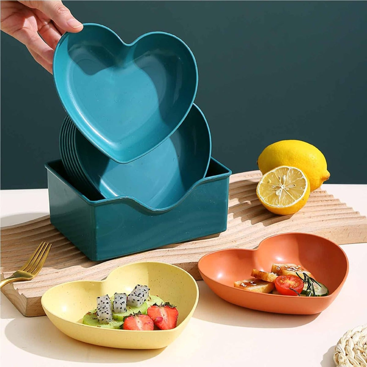 Ciotole a forma di cuore in plastica blu con verdure e limone, più arancione e gialla