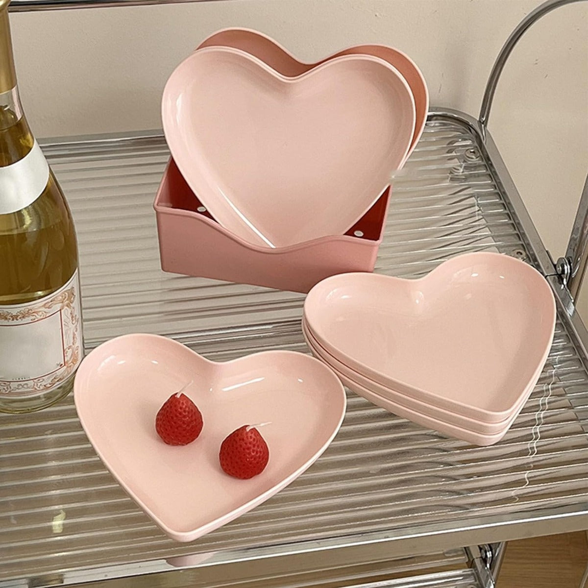 Ciotole a forma di cuore in plastica rosa, impilate e con due fragole