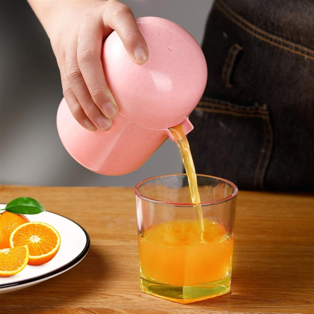 Spremiagrumi manuale rosa mentre versa succo in un bicchiere