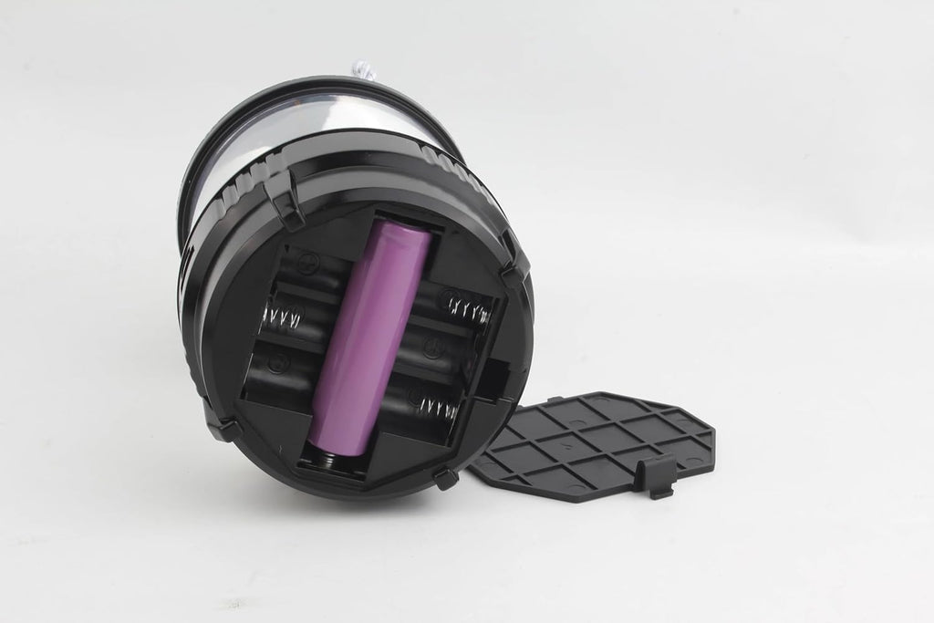 Proiettore LED da palco nero con vano batterie aperto e batteria viola inserita
