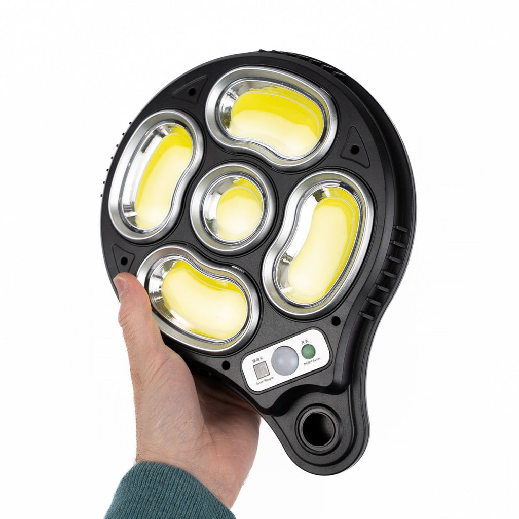 Proiettore solare nero con 5 LED COB accesi gialli e pulsanti sul pannello.