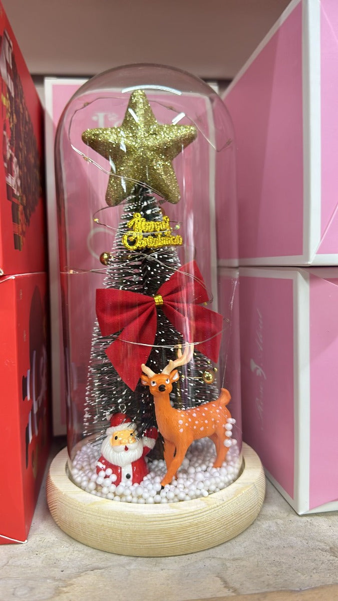 Cupola di vetro con albero illuminato, stella dorata, fiocco rosso e renna