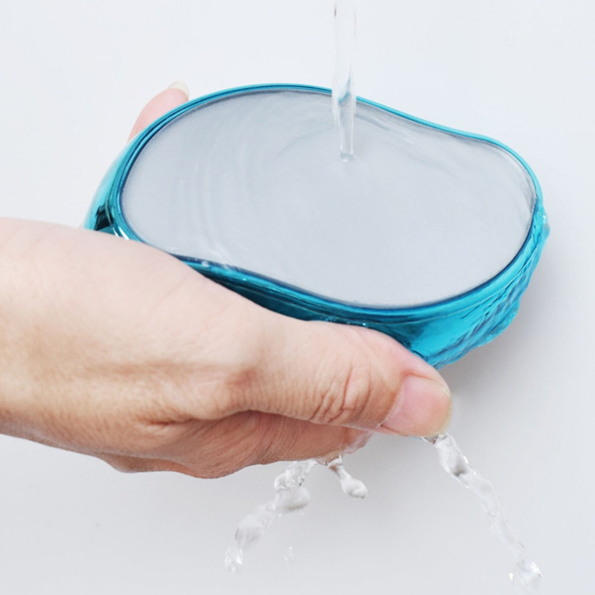 Depilatore portatile turchese sotto getto d’acqua, mano che lo sostiene