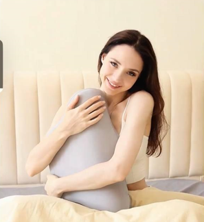 Cuscino cervicale in memory foam grigio a forma di U, usato sul letto