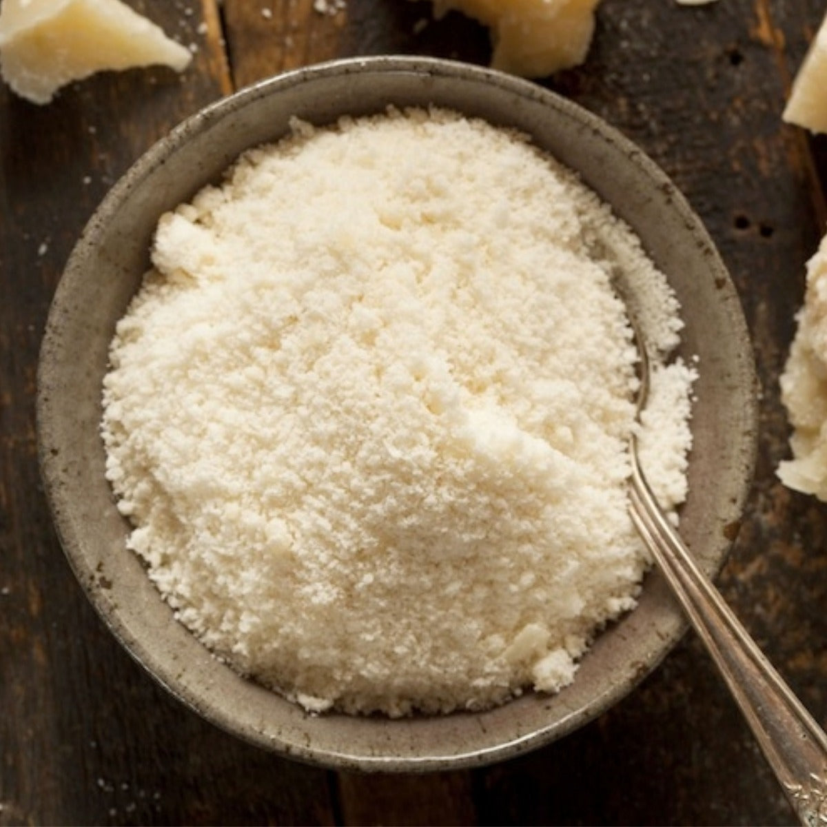 Formaggio grattugiato fine in ciotola con cucchiaio