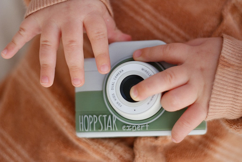 Fotocamera per bambini bianco-verde con obiettivo, tenuta dalle mani