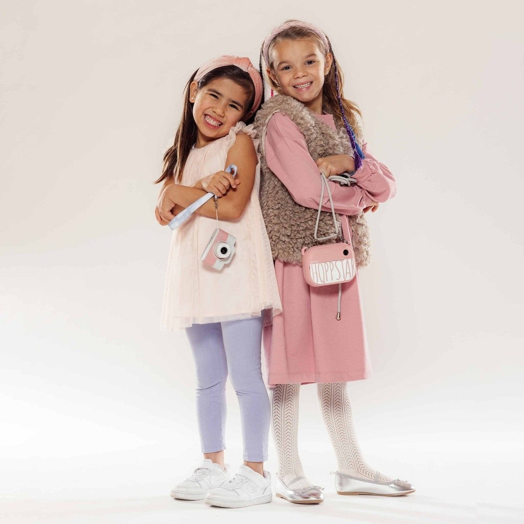 Fotocamere per bambini: rosa e bianca, con tracolla, in mano ai bambini