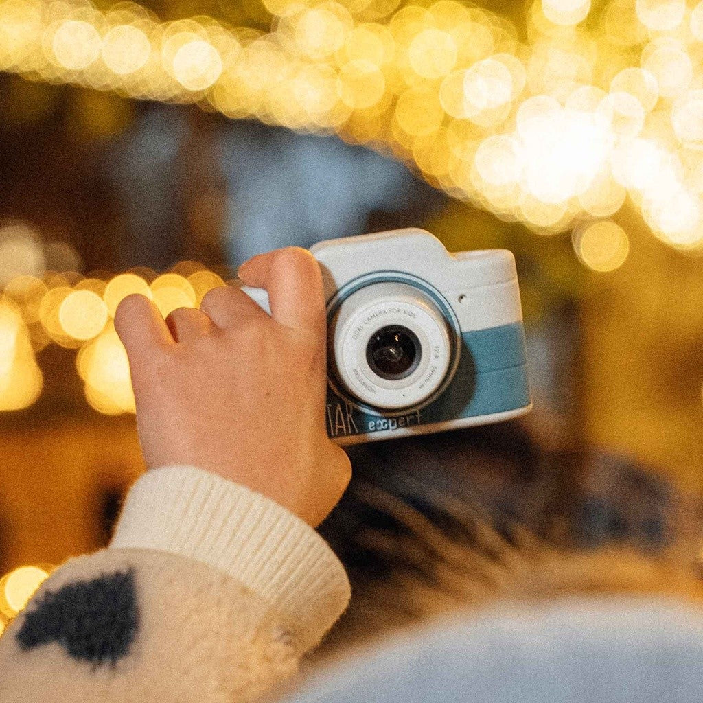 Fotocamera per bambini bianca e azzurra con mano che la impugna